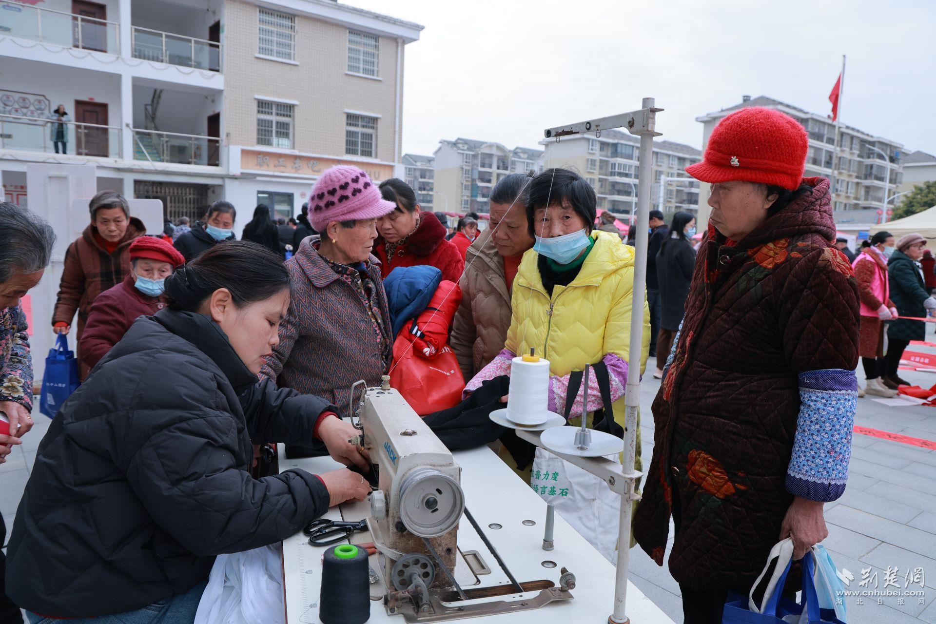 衣物縫補(bǔ)攤前，志愿者飛針走線為居民修補(bǔ)破損衣物.jpg.jpg